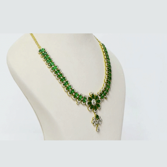 An exquisite necklace and earring set featuring oval emeralds with mutual-cut diamond centres, accented by round diamonds for timeless elegance, luxurious brilliance, and sophisticated charm. (GDNE0535)