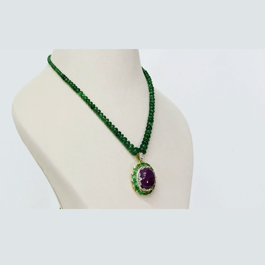 A captivating pendant featuring a ruby cabochon encircled by emerald-cut ovals and diamonds, strung with emerald beads for a bold fusion of colour, brilliance, and timeless luxury. (GDPE0408)