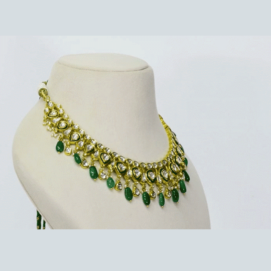An elegant necklace and earring set featuring diamond polki framed by a vivid green circle, strung with emerald maniya and pearls. Blending heritage craftsmanship with refined luxury, it’s perfect for graceful, modern celebrations. (KMNE3588)