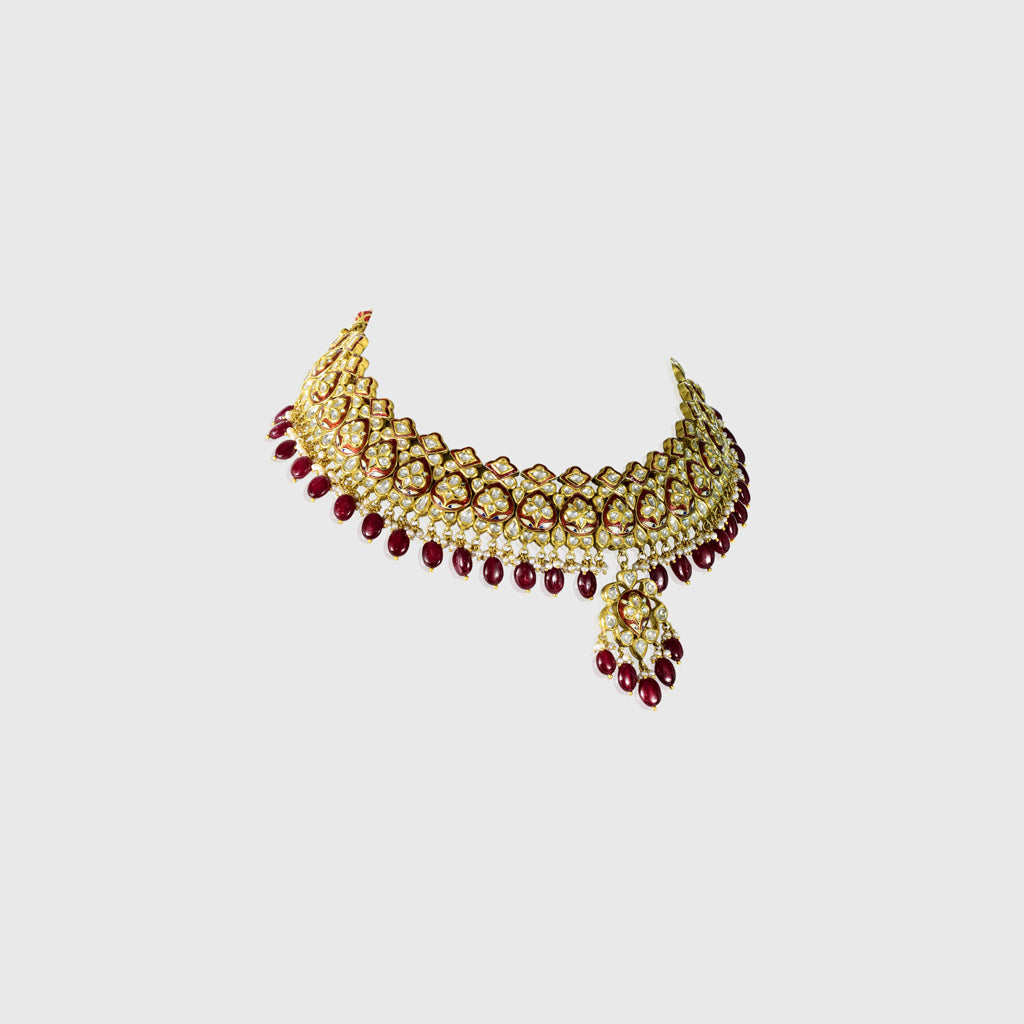 Beautiful red enameled flower design necklace and earrings set with sparkling uncut diamond polki, strung with ruby maniya and pearls. Perfect to add a touch of tradition and elegance to any special occasion.(KMNE3608)