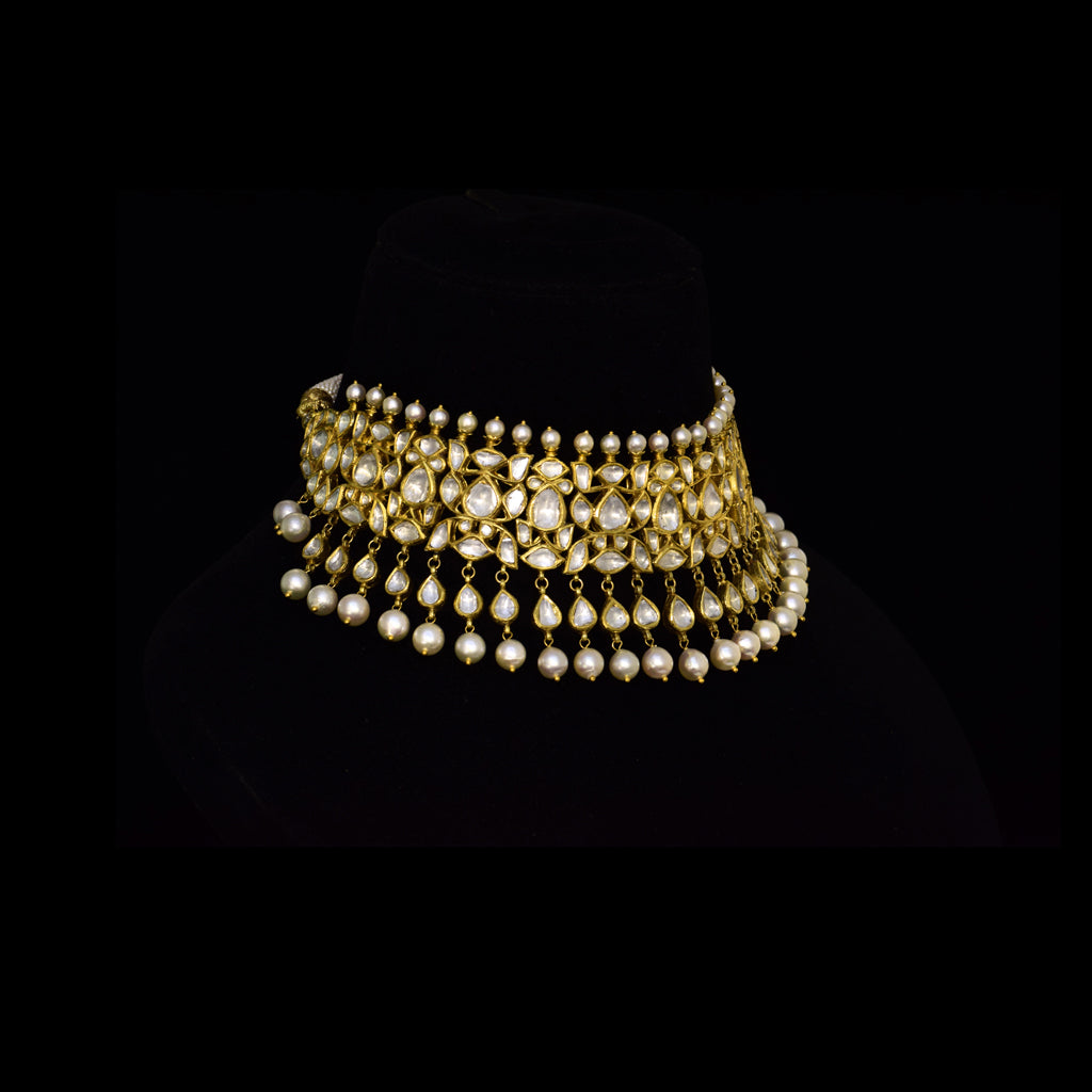 Elevate your style with this stunning semi-choker necklace and earring pair, featuring dazzling uncut diamond polki and a striking larger center stone, beautifully strung with pearls. Perfect for adding royal charm to any special occasion.(KMNE3611)