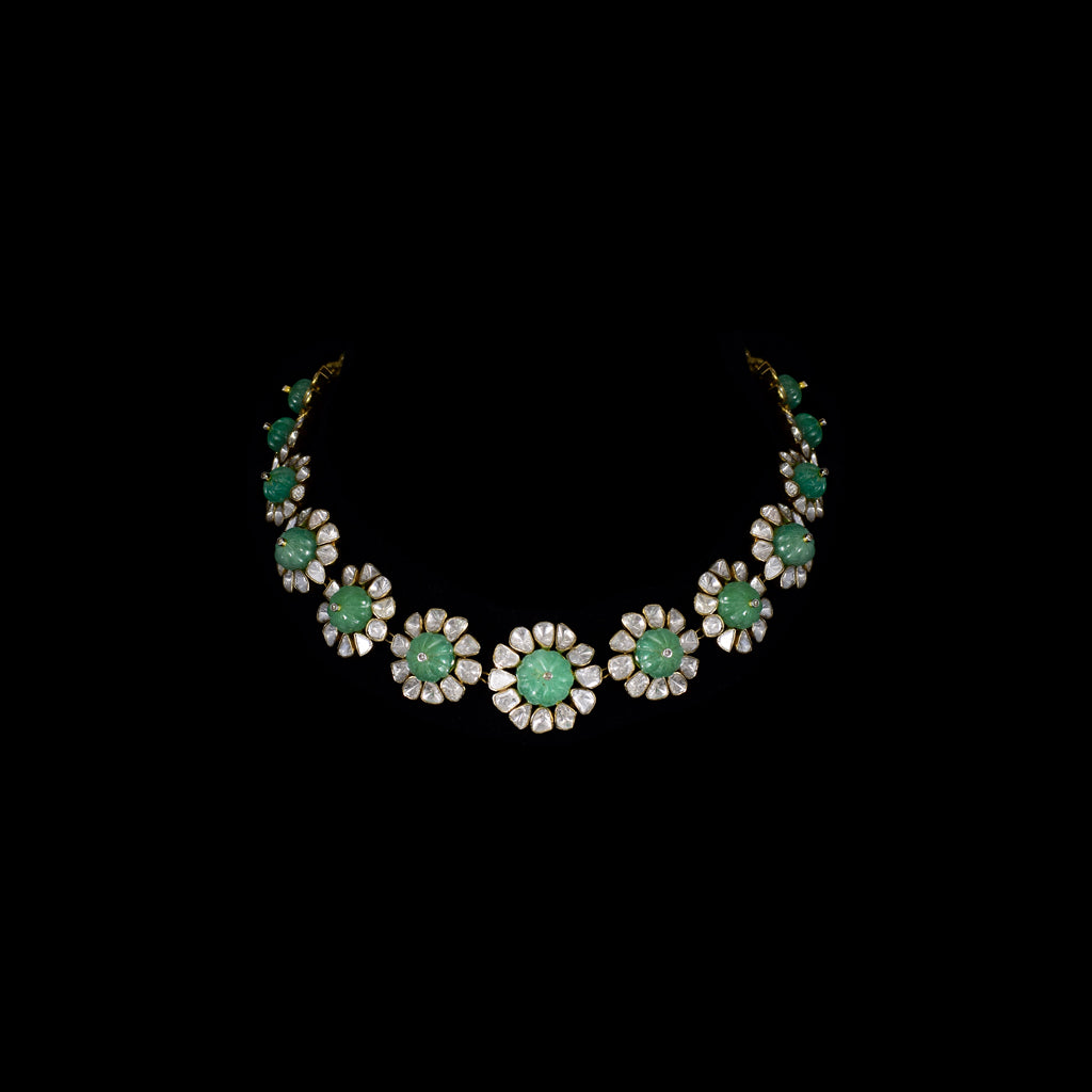Discover refined elegance with this fusion-style necklace set, featuring a carved emerald centerpiece surrounded by uncut diamond Polki. A perfect harmony of tradition and modernity, crafted to make a statement.(KMNE3614)