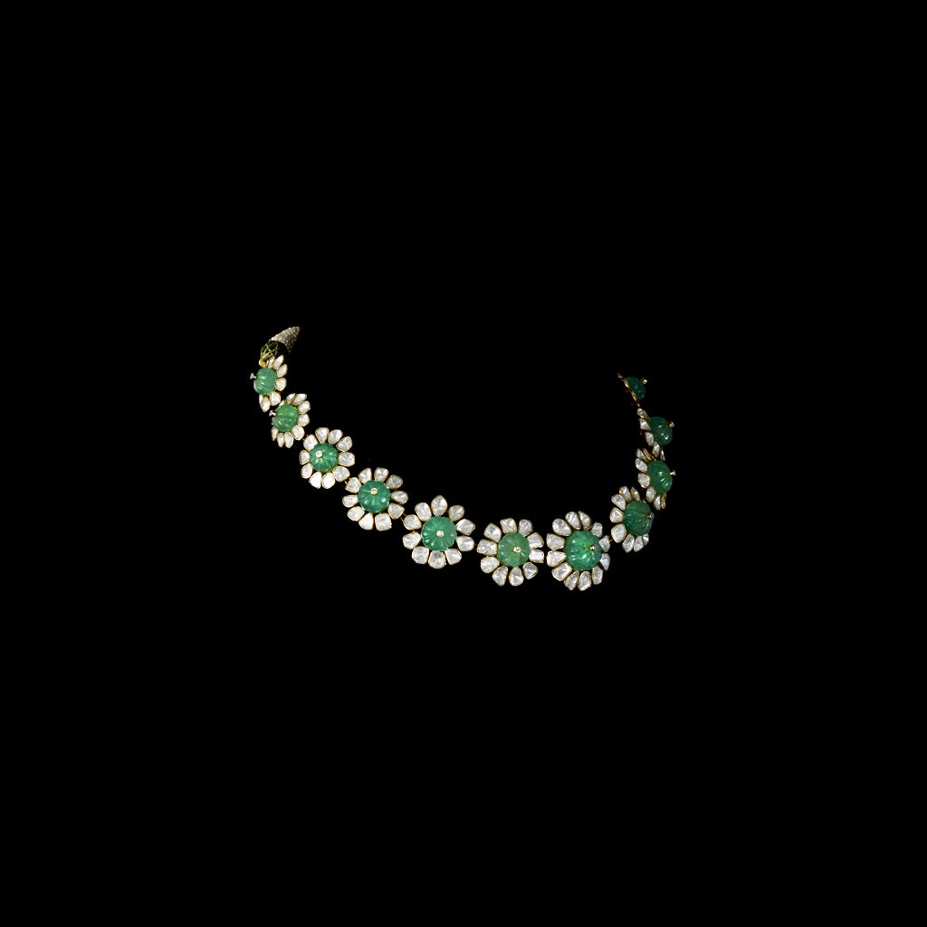 Discover refined elegance with this fusion-style necklace set, featuring a carved emerald centerpiece surrounded by uncut diamond Polki. A perfect harmony of tradition and modernity, crafted to make a statement.(KMNE3614)
