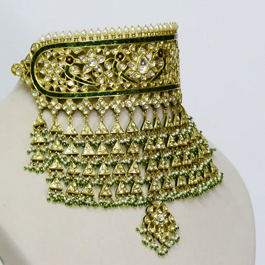 A traditional Rajasthani aad necklace and earring set crafted with diamond polki, accented by rich green stones and pearl stringing. An opulent expression of royal heritage and timeless bridal elegance. (KMNE3663)