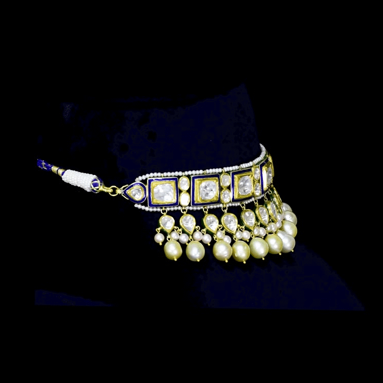 A regal blue enamelled choker set in gold, showcasing bold oversized polki diamonds framed with intricate detailing, finished with cascading South Sea pearl fringes and perfectly matched statement earrings for timeless grandeur. (KMNE3720)