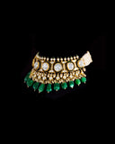 A majestic choker showcasing large polki diamonds set in striking green-enamelled gold, layered with intricate detailing, finished with cascading emerald drops and pearl fringes—opulent, bold, and exquisitely regal. (KMNE3724)