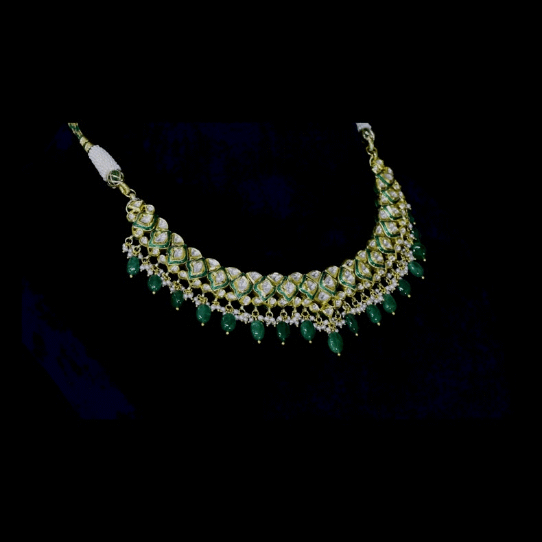A stunning necklace set with gold and diamond polki, featuring green enamelled detailing, accented with emerald maniya drops and delicate pearls, creating a perfect blend of heritage elegance and vibrant sophistication. (KMNE3732)
