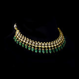 An elegant gold necklace set featuring polki diamonds with blue enamel detailing, accented by emerald maniya and delicate pearl hangings, offering a graceful blend of tradition and refined contemporary luxury. (KMNE3739)