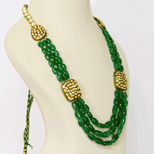 Three strands of vibrant emerald maniya paired with red meenakari diamond Polki motifs create a timeless necklace blending royal heritage with contemporary elegance beautifully.(KMNE3786)