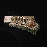 Handcrafted to perfection, this Diamond Polki choker and earrings blend classic artistry with elegant emerald drops and pearl accents.(KMNE3797)