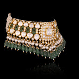 Handcrafted to perfection, this Diamond Polki choker and earrings blend classic artistry with elegant emerald drops and pearl accents.(KMNE3797)
