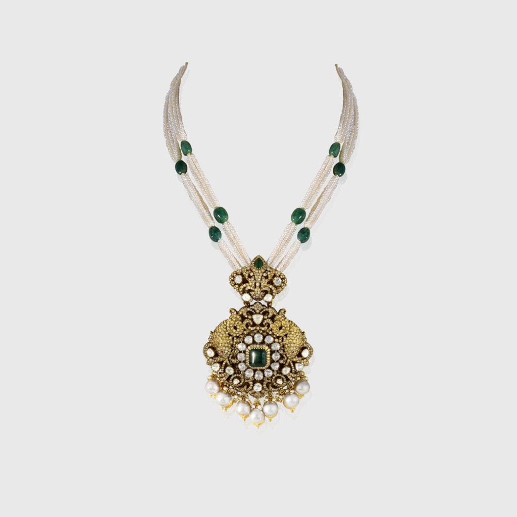 Discover refined elegance with this fusion-style pendant, showcasing uncut diamond Polki, round diamonds, and a central emerald. Strung with pearls and long emerald beads, it’s a striking blend of tradition and modern sophistication.(KMPE1327)