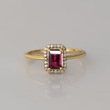 Celebrate timeless beauty with an emerald-cut pink tourmaline ring, gracefully highlighted by a shimmering halo of brilliant round diamonds.(PGDR0472)