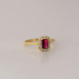 Celebrate timeless beauty with an emerald-cut pink tourmaline ring, gracefully highlighted by a shimmering halo of brilliant round diamonds.(PGDR0472)