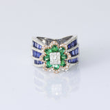 Featuring a diamond cluster center, encircled by vivid emeralds and accented with channel-set sapphires, this ring is designed to make a powerful statement. (PGDR0523)