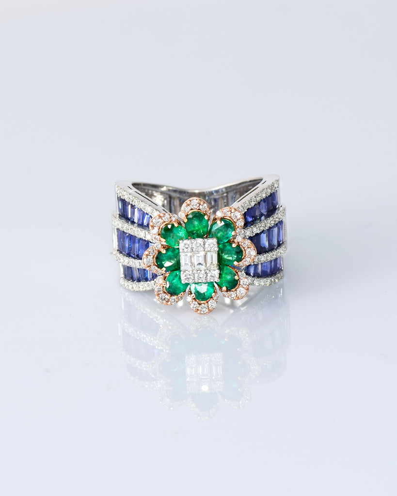Featuring a diamond cluster center, encircled by vivid emeralds and accented with channel-set sapphires, this ring is designed to make a powerful statement. (PGDR0523)