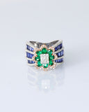 Featuring a diamond cluster center, encircled by vivid emeralds and accented with channel-set sapphires, this ring is designed to make a powerful statement. (PGDR0523)