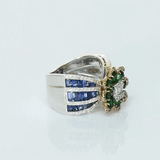 Featuring a diamond cluster center, encircled by vivid emeralds and accented with channel-set sapphires, this ring is designed to make a powerful statement. (PGDR0523)