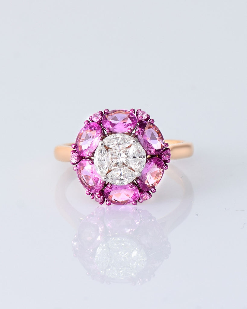 A radiant round diamond embraced by a halo of vivid pink sapphires—where timeless brilliance meets feminine charm. (PGDR0524)