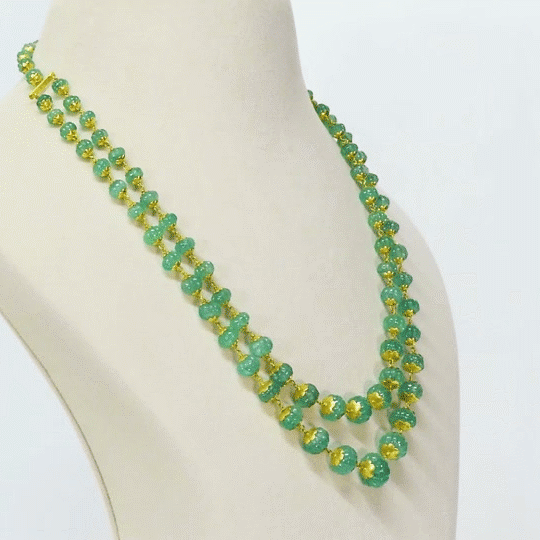 A luxurious double-line string of intricately carved emerald beads, delicately strung on gold wire, radiating timeless elegance and sophistication. (STRG348)
