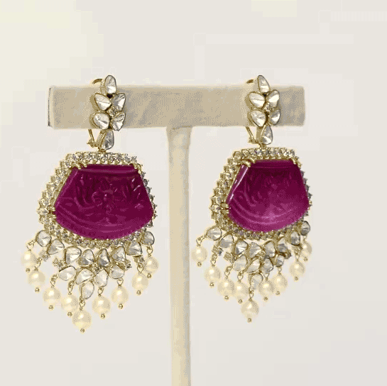 our luxurious long earrings adorned with intricately carved ruby stones, shimmering diamond polki, and radiant diamond rounds. Complete with delicate pearl hangings, these earrings exude timeless sophistication and charm. (GDE0437)